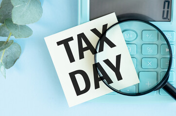 Blue card with tax day text, with calculator next to it. Payment of taxes and tax deadlines.