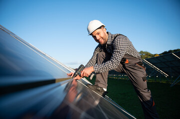 Man worker mounting photovoltaic solar panels. Engineer in helmet installing solar module system. Concept of alternative, renewable energy