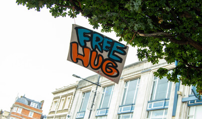 A Sign That Has Been Hung From A Tree Offering Free Hugs To Brighten A Person's Day