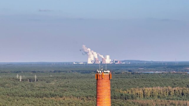 Telephoto drone video of the chimney at Knappenrode Energy Plant, with the Boxberg coal power plant visible in the background. Drone move right.