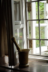 mortar and pestle against the background of an open window in an old house