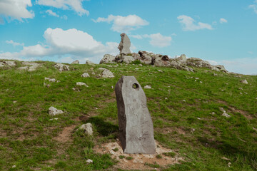Ancient standing stones on a grassy hill under a blue sky in Armenia during daylight