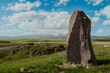 Ancient stone monument stands tall against the backdrop of Armenian mountains and blue skies