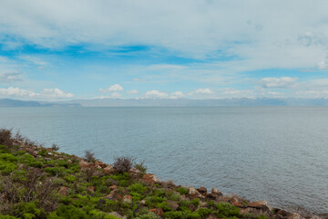A serene view of Lake Sevan surrounded by lush greenery in Armenia under a cloudy sky