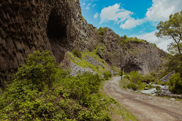 Scenic landscape of Armenia featuring rugged cliffs and a winding path by the river