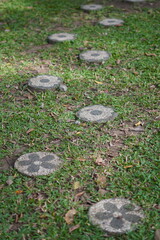 A path with round zigzag stepping stones as a direction for footsteps with grass in a garden