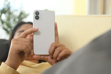 Young woman relaxing in living room and checking notifications on smartphone