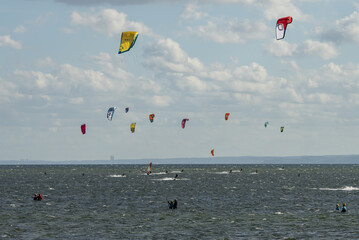 People swim on the sea on a kiteboard or kitesurfing. Kitesurfing lessons on the bay. Summer sport learning how to kitesurf. Kite surfing on bay. Hel Peninsula,Puck bay, Jastarnia, Poland.
