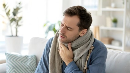 Man with sore throat wrapped in scarf indoors
