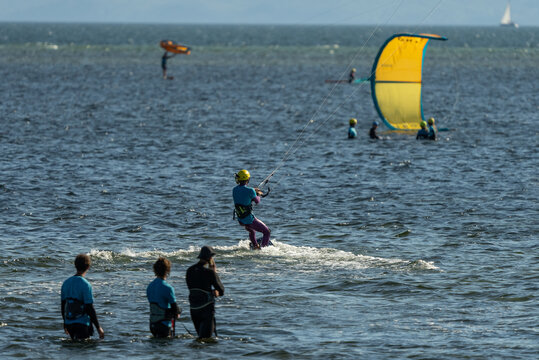 People swim on the sea on a kiteboard or kitesurfing. Kitesurfing lessons on the bay. Summer sport learning how to kitesurf. Kite surfing on bay. Hel Peninsula,Puck bay, Jastarnia, Poland.
