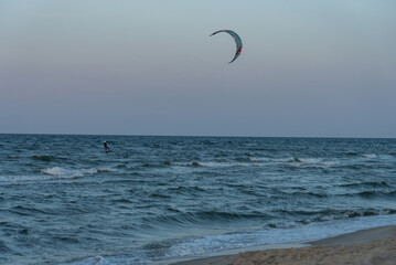 People swim on the sea on a kiteboard or kitesurfing. Kitesurfing lessons on the bay. Summer sport learning how to kitesurf. Kite surfing on bay. Hel Peninsula,Puck bay, Jastarnia, Poland.