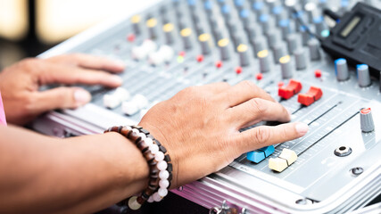 A close-up of a person adjusting an audio mixing console, focusing on hand movements with control...