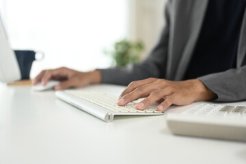 Close up of businessman typing on wireless keyboard at modern workspace
