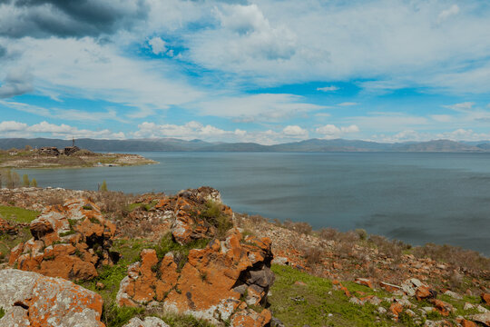 Scenic view of Sevanavank Monastery and Lake Sevan against a backdrop of clouds and mountains