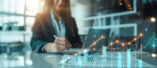 Focused businesswoman working on a laptop, analyzing financial data reflected in an augmented reality interface with rising graphs, signifying growth and profit in a modern office setting.