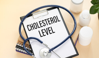 Stethoscope and paper note with text CHOLESTEROL LEVEL. Health concept