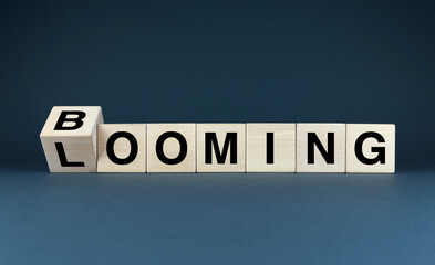 Word Booming spelled out with wooden blocks, while a tilted B block hints at the word Looming.