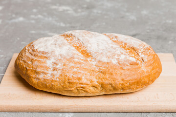 Freshly baked bread on cutting board against white wooden background. perspective view bread with copy space