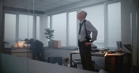 Office robbery or murder case: Investigation team at crime scene. Female forensic scientist takes photos of evidence, then talks to male detective. African American policeman looks for fingerprints.