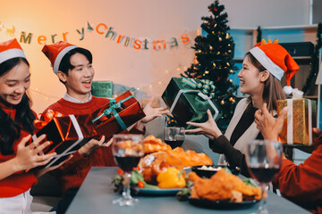 Group of young Asian man and women as friends having fun at a New Year's celebration, holding gift...