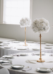 A wedding table decorated with white roses on tall golden candlesticks.