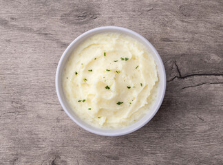 Mashed potatoes in a bowl over wooden table