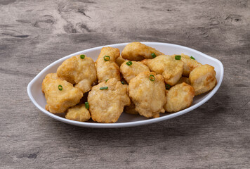 Breaded chicken bites in a plate over wooden table