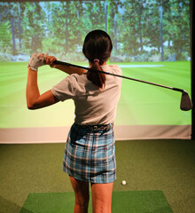 Fototapeta premium Girl playing golf on screen and golf simulator concept