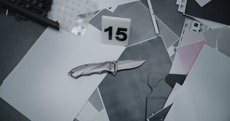 Bank robbery or murder case. Top view on murder weapon knife lying next to numbered marker. Papers...