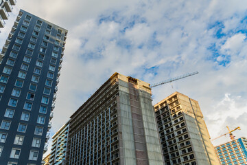 Modern apartment buildings with glass balconies standing tall under a blue sky with white clouds, showcasing contemporary urban architecture