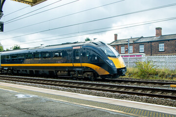 Obraz premium A Passing High Speed Passenger Train Flying Past A Train Station Platform