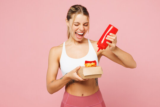 Young cool woman wear white top casual clothes hold box with french fries potato add sauce isolated on plain pastel light pink background. Proper nutrition healthy fast food unhealthy choice concept.
