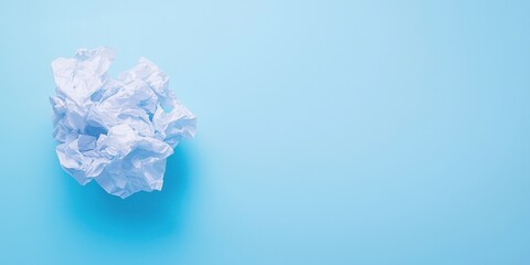 Crumpled paper ball on a light blue background, representing waste and recycled materials.