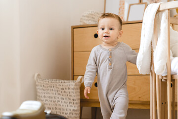 Fototapeta premium First steps. Little small caucasian child kid toddler walking at home, learning and exploring the world. Parenthood and child care concept