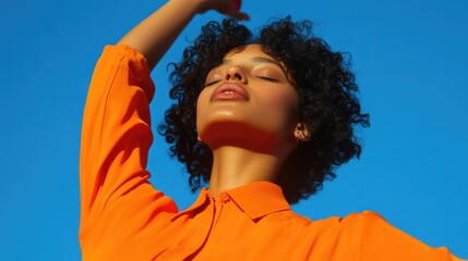 A woman stretches her arms while wearing an orange shirt