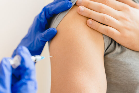 Vaccination concept. Closeup cropped human`s forearm and doctor nurse taking shot injection vaccine with syringe in clinic hospital. Coronavirus Covid19 vaccinated