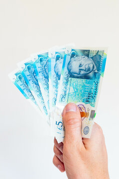 5 five pound sterling (GBP) notes held in his right hand.