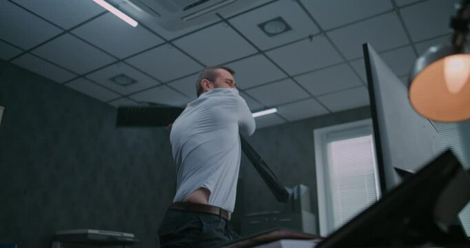 Slow motion of aggressive office worker smashing computer monitor with keyboard, throwing papers from desktop and screaming. Furious businessman loses temper in fit of rage. Financial loss or firing.