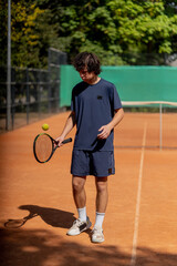 professional tennis court young curly guy trains hitting the ball with tennis racket professional preparation for the game