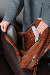 woman holds a brown leather backpack. open, empty bag
