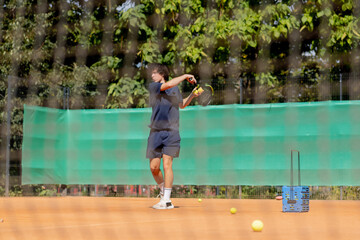 professional tennis court young curly guy technically performs the first serve in the game examines...