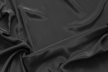 Textile background of black fabric with soft folds in lower left corner and empty space for text on top. Beautiful backdrop for design or decoration. Mock up, flat lay, copy space, top view, blank