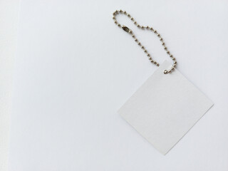A metal ball chain for tags and a white label are lying on the table. Product price tags. Advertising background, space for text.