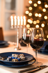 A table with a blue plate and two wine glasses with candles on it