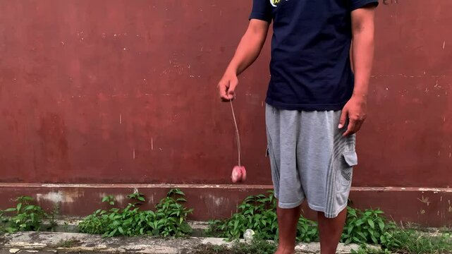 4K video of male hand playing yoyo. A yoyo is a toy consisting of two disks connected by an axle around which a string is wound. A yoyo is thrown down on a string and can be returned to the hand