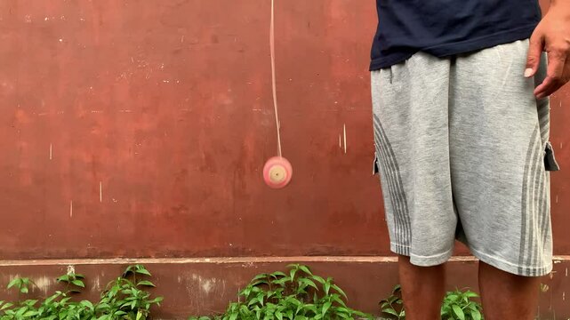 4K video of male hand playing yoyo. A yoyo is a toy consisting of two disks connected by an axle around which a string is wound. A yoyo is thrown down on a string and can be returned to the hand
