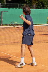 on professional tennis court a young curly guy practices hitting a tennis ball practice of a low kick