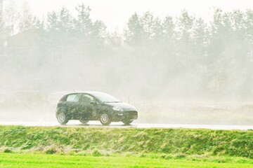 Fototapeta premium Car driving on rainy day through heavy downpour