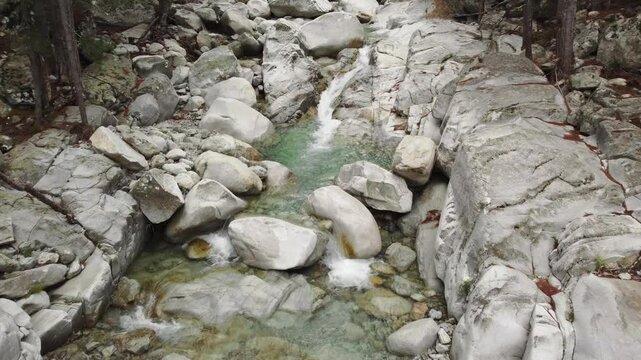 Peaceful river stream in Restonica valley, small waterfall, drone flying down