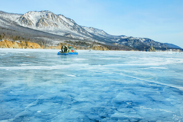 Naklejka premium A hovercraft on the transparent ice of the frozen Lake Baikal. Winter trip.